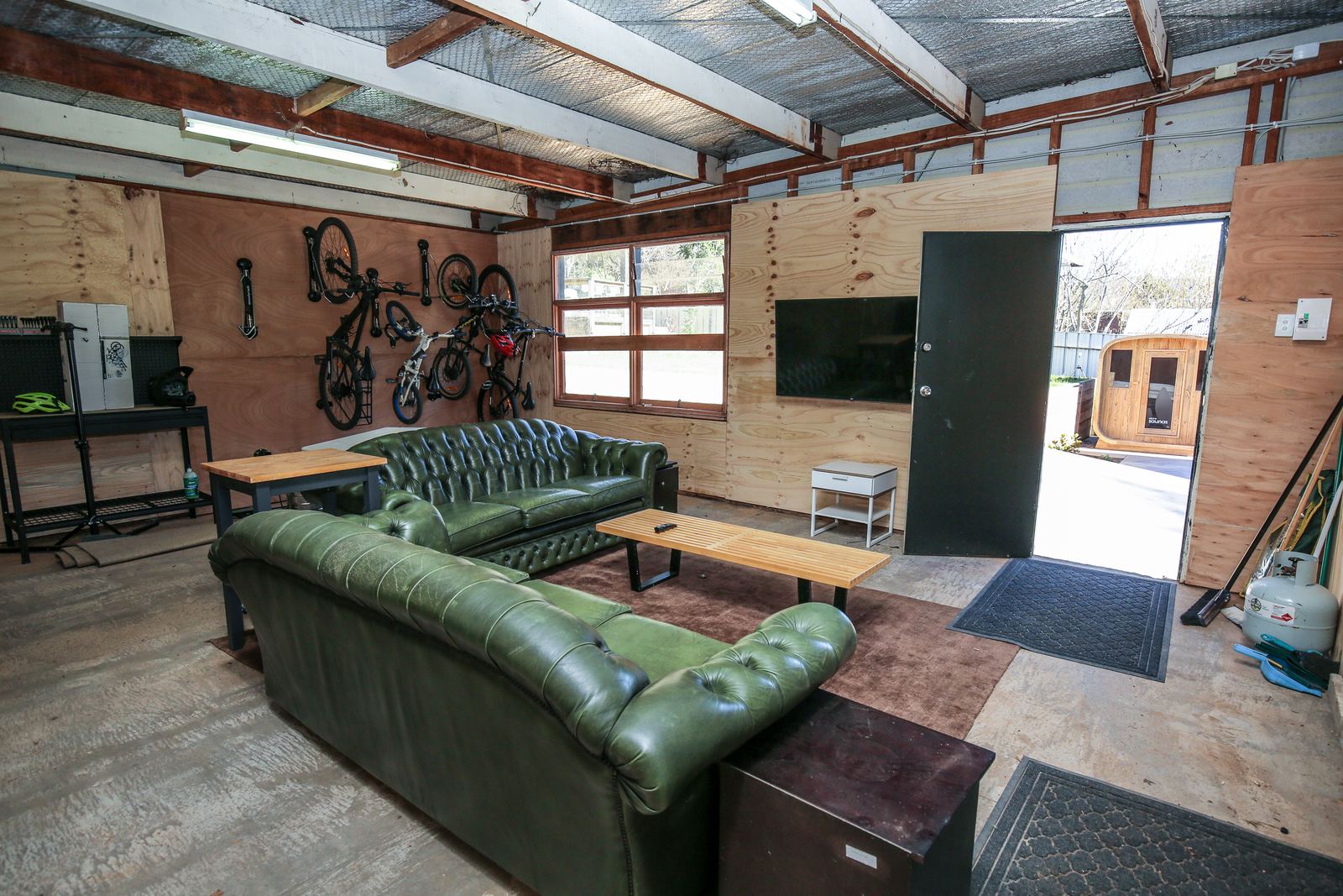 Bikes hung on the wall racks in the lockable garage, with the garage lounge sofas in front