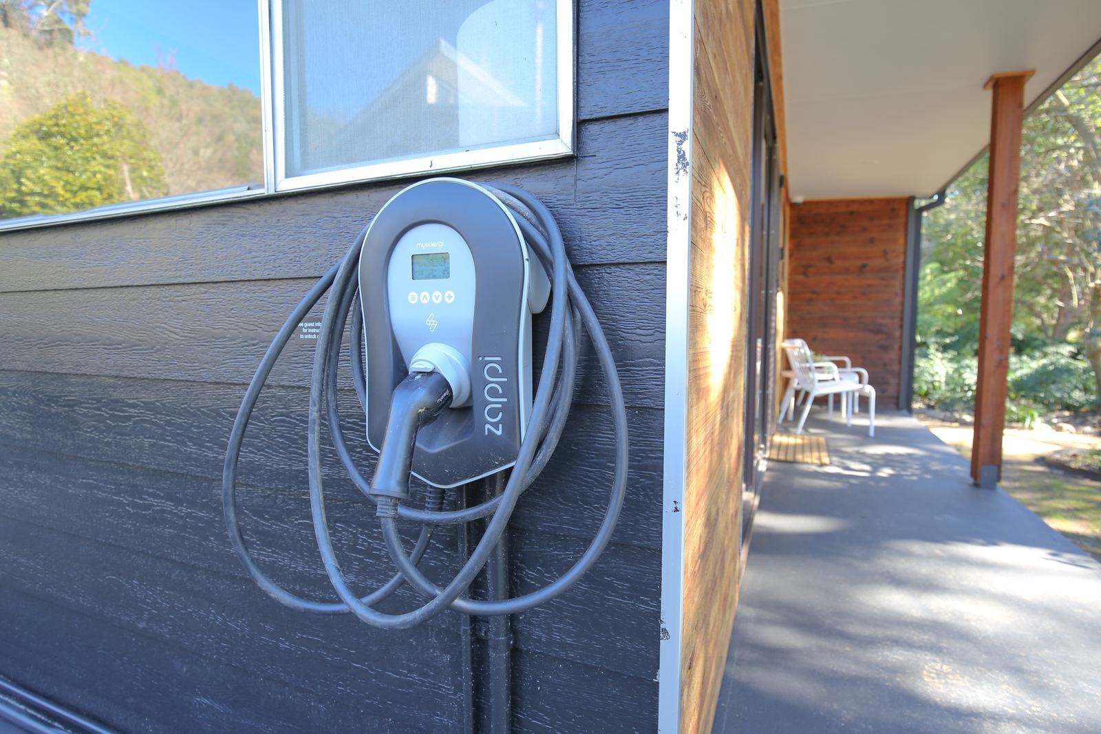 The myenergi zappi charger on the front wall of the house, with its tethered cable