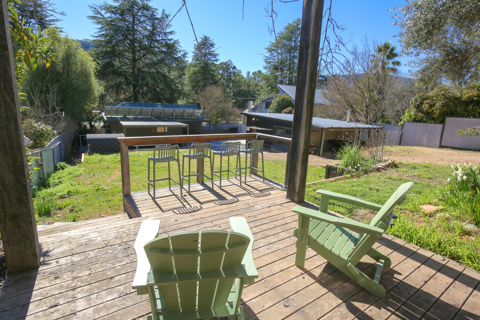 The timber deck with two green chairs, looking down over the yard to the hills