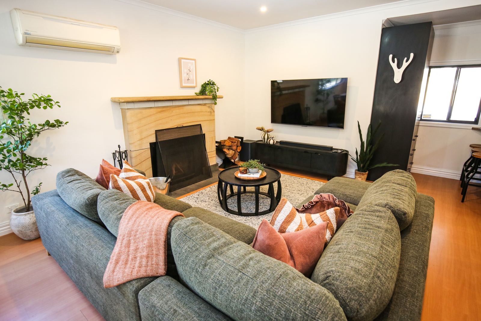 The living room sofa in front of the sandstone-framed wood fire